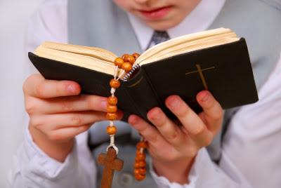 Catholic child reading a Bible with a Rosary